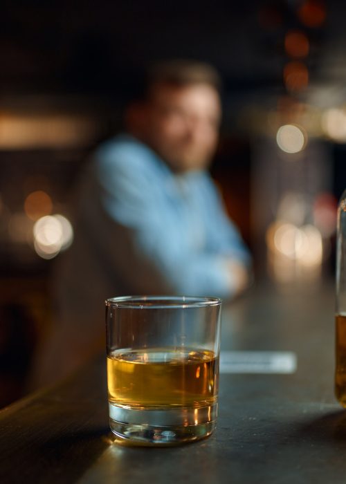 Bottle of alcohol and glass on counter in bar